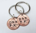 pair of 2 anniversary, valentine's day penny keychains with couples initials stamped in the center, heart around the penny year, and anniversary date stamped below the initials.