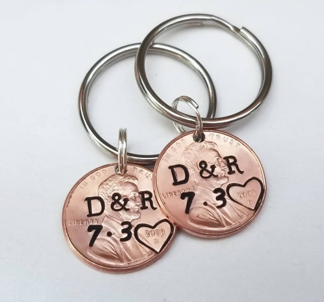 pair of 2 anniversary, valentine's day penny keychains with couples initials stamped in the center, heart around the penny year, and anniversary date stamped below the initials.